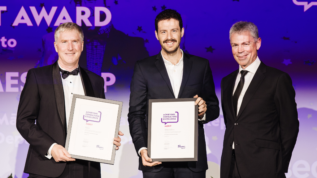 Holmes Group at the ACE Awards. Three men standing on stage with their award.