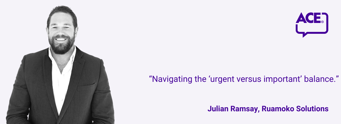 Julian Ramsay, dark hair, beard, smiling, wearing a suit.