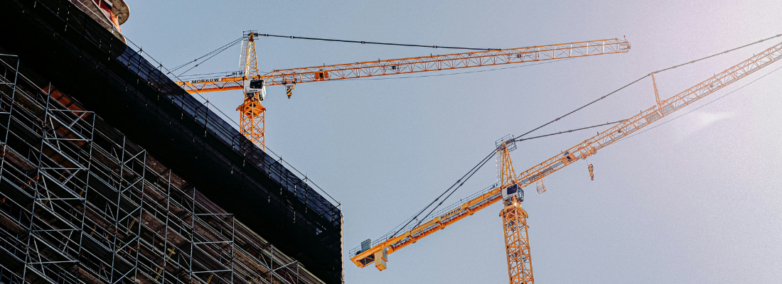 Cranes construction a large building on a sunny day
