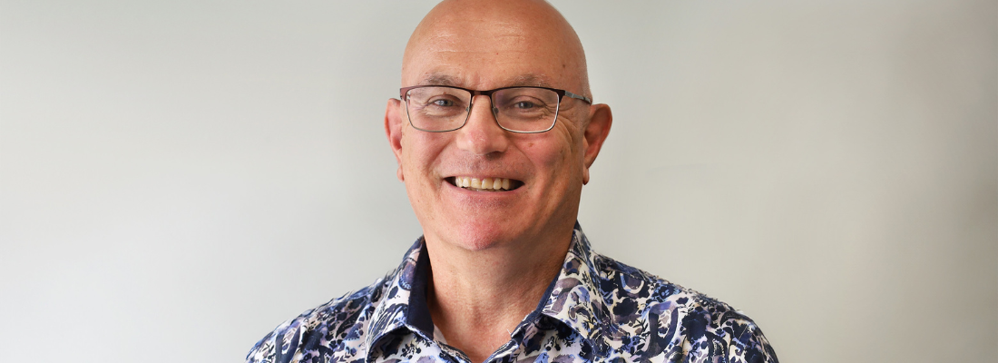 A man in a blue shirt smiling at the camera