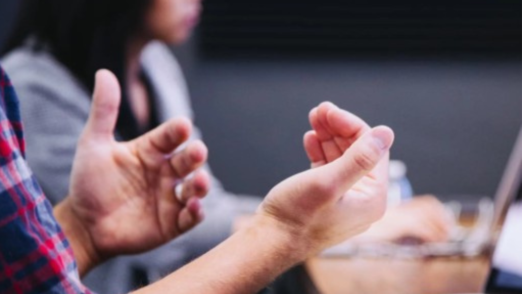 A closeup of someone gesturing at a meeting with their hands a meeting.