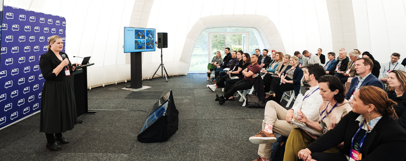 A crowd watching a woman speak in front of a screen at Futurespace 2025