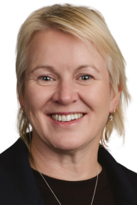 White female, short blonde hair, smiling, earrings, dark top and jacket, headshot.