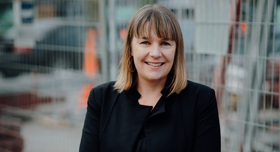 White female, shoulder length light brown hair, smiling, suit.