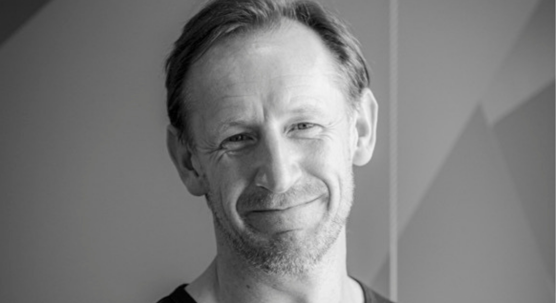 White male, fair haired, smiling, headshot.
