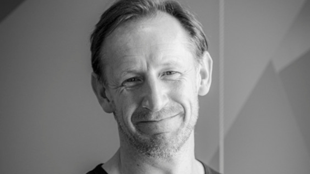 White male, fair haired, smiling, headshot.