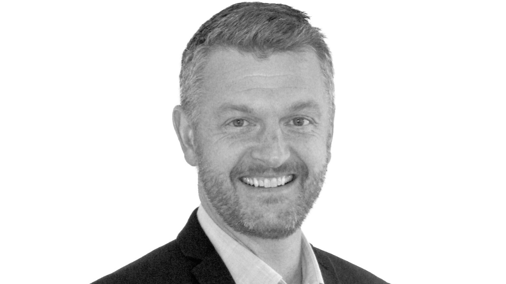 Headshot, male, fair hair, beard, smiling, suit.